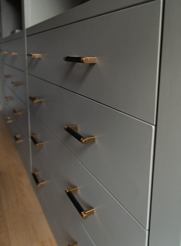 Close-up of brass and black cabinet pulls on custom storage drawers.